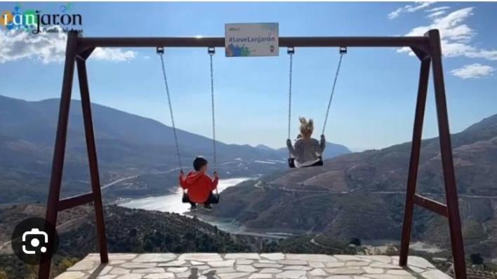two people sitting on a swing in the mountains at Casa rural Los Rosales in Lanjarón