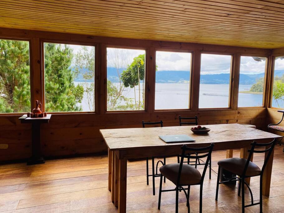 帕斯托Cabaña en La Laguna de la Cocha的一间有桌椅和窗户的餐厅