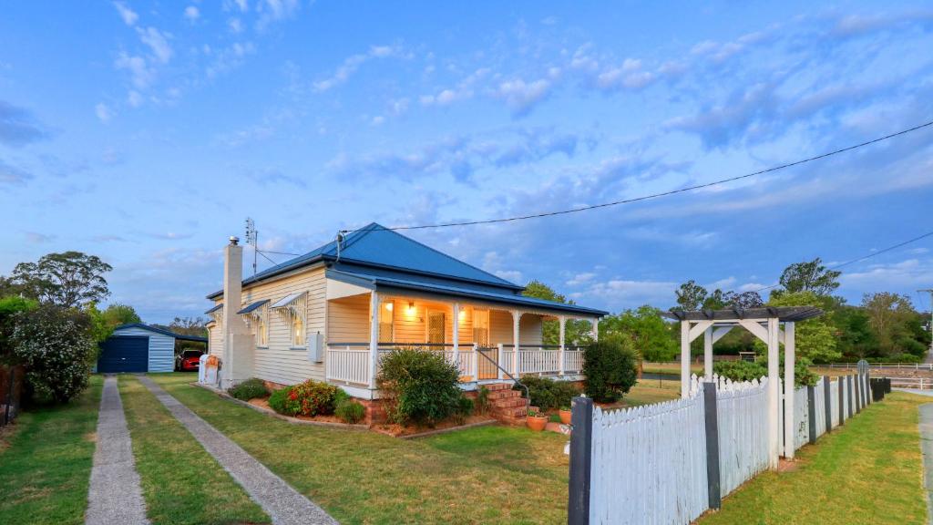 a house with a blue roof and a white fence at Creekview Cottage - 70 Lock Street in Stanthorpe