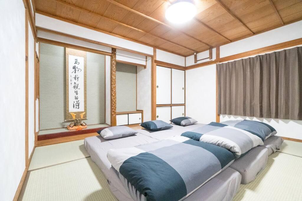 duże łóżko w pokoju z oknami w obiekcie LAINA MINOH＊1棟貸切＊ w mieście Minoo