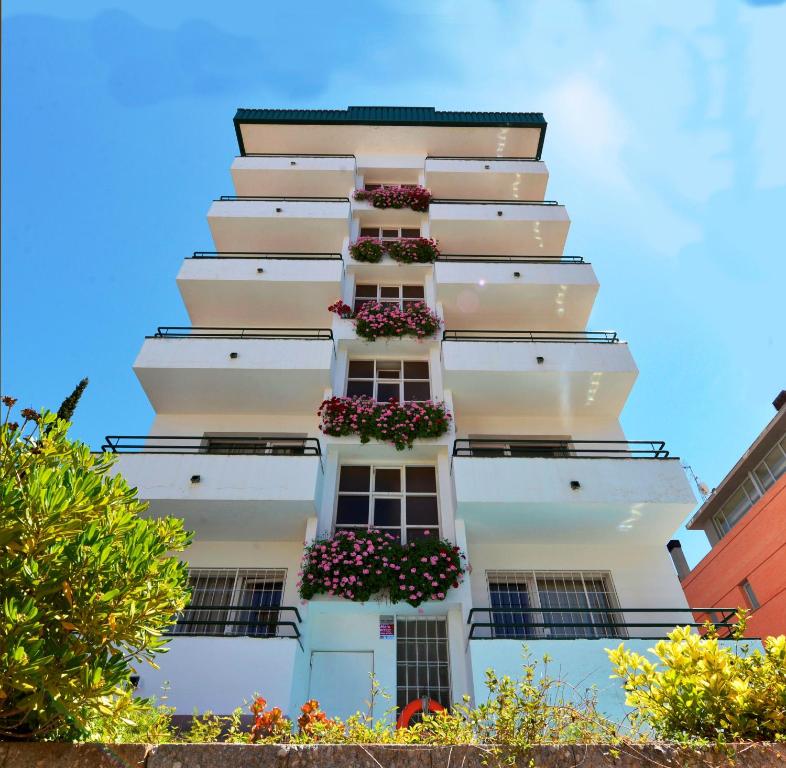 een wit appartementencomplex met bloembakken op de balkons bij Hostal Magnolia in Lloret de Mar
