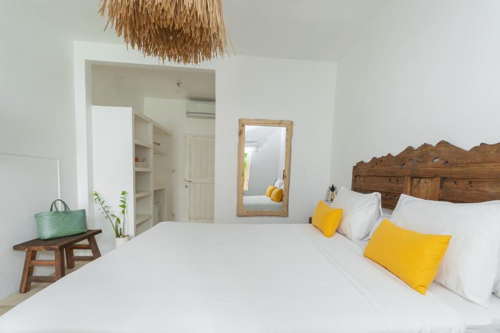a white bedroom with a large bed with yellow pillows at The Room Padang-Padang in Uluwatu