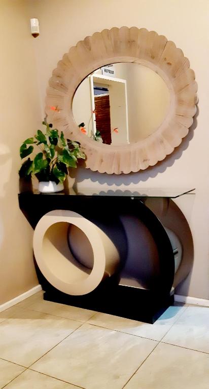 a bathroom with a toilet with a mirror at Bhotani Lodge in Port Elizabeth