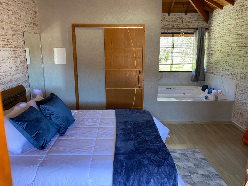 um quarto com uma cama com almofadas azuis e uma banheira em Villagio da Mantiqueira em Monte Verde