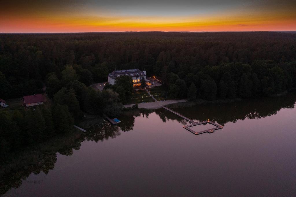 z góry widok na dom nad jeziorem o zachodzie słońca w obiekcie Ośrodek Gawra w Nidzicy