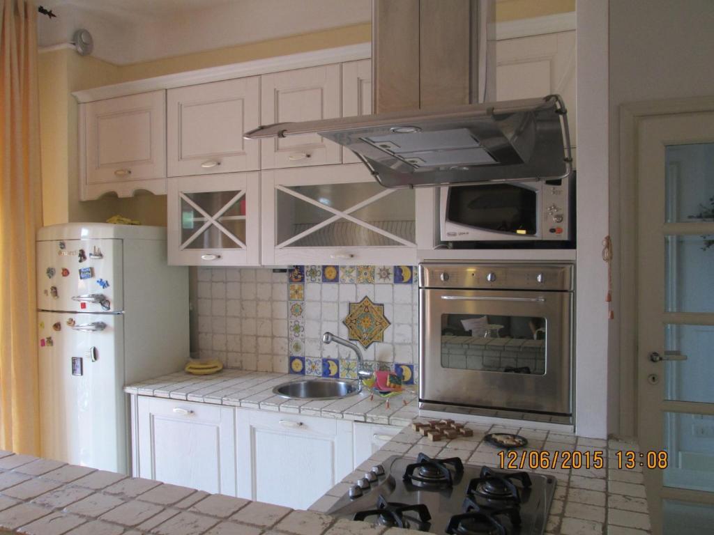 a kitchen with white cabinets and a stove top oven at Gemma's Apartment in Sarzana