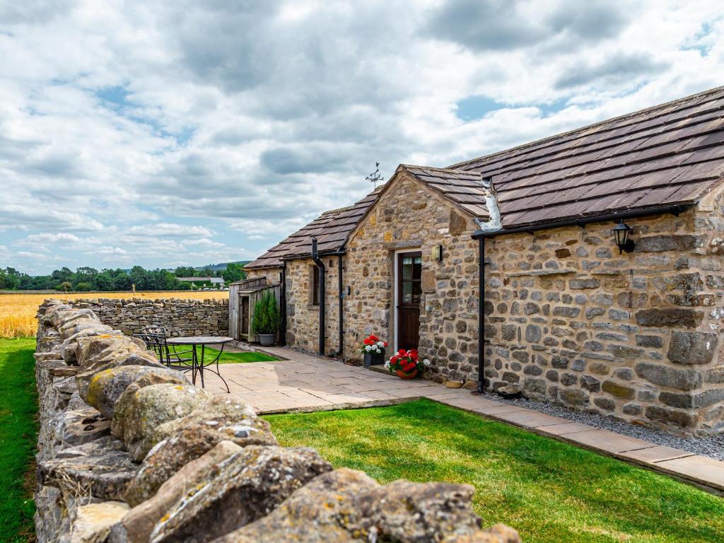 a stone barn with a stone wall and a table at Curlew Barn in Middleham