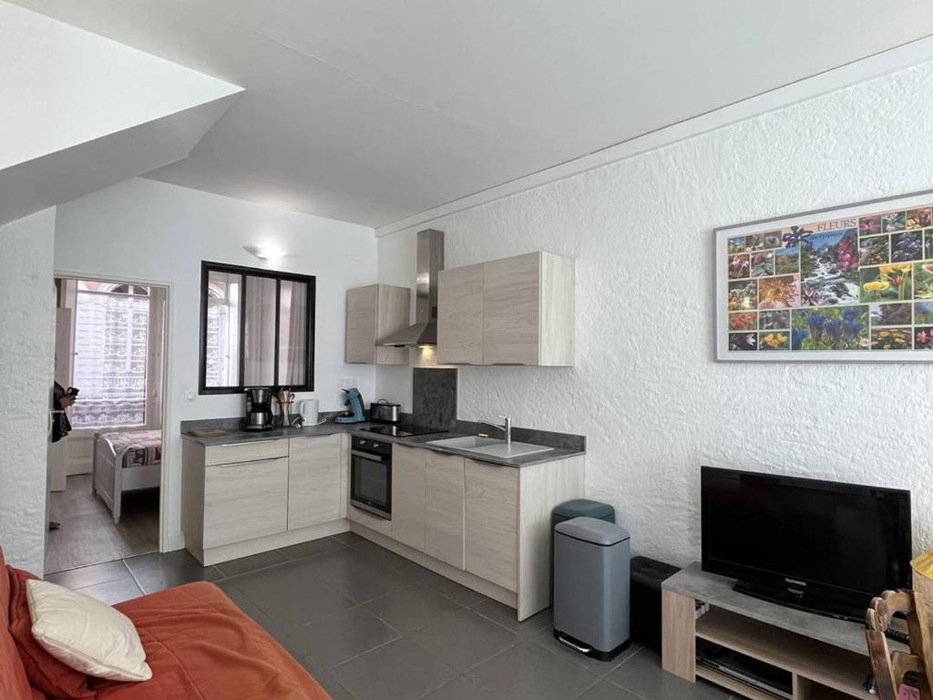 une cuisine avec des armoires blanches et une télévision à écran plat dans l'établissement Appartement 6/8 pers, centre-ville avec jardin, proche télécabines - FR-1-234-311, à Cauterets