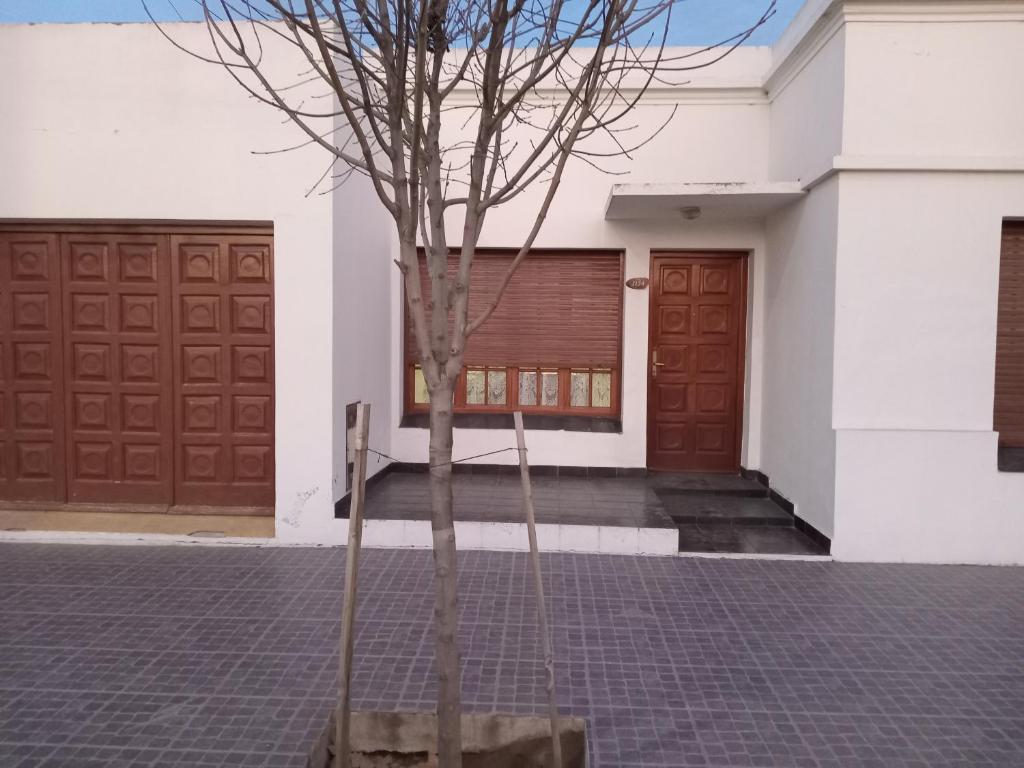 un árbol frente a un edificio con dos puertas de garaje en Elena en Carhué