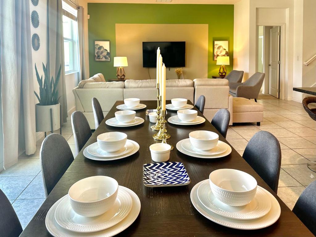a dining room with a table and chairs and a living room at Heated Pool Vacation Villa, Theme Room, Gated Community near Disney, Sleeps 12! in Kissimmee