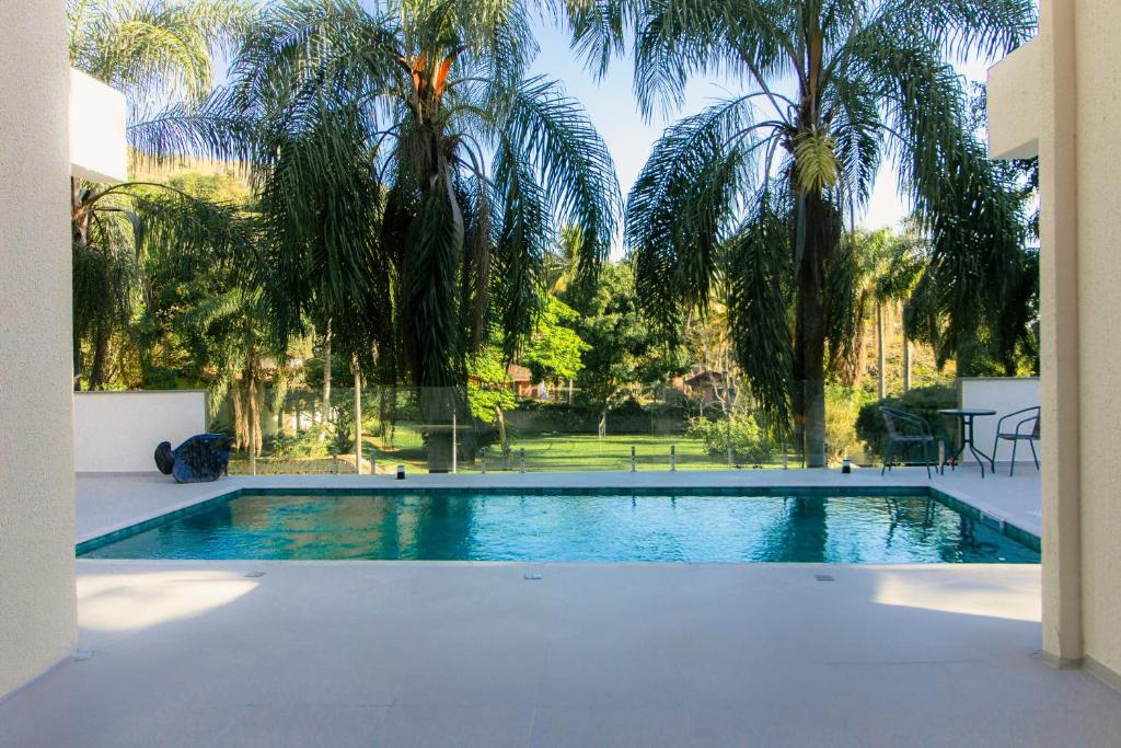uma piscina com palmeiras ao fundo em Zaya Beach House em Ilhabela em Ilhabela