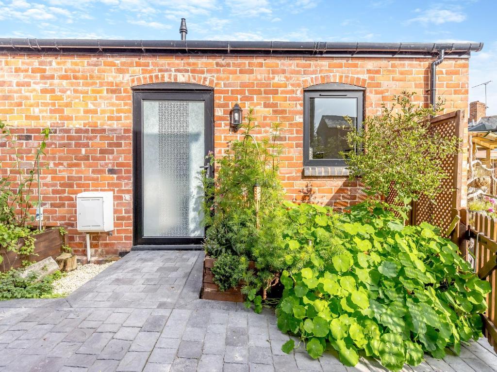 a brick house with a black door and some plants at Molly Veroni - Uk43592 in Ellesmere