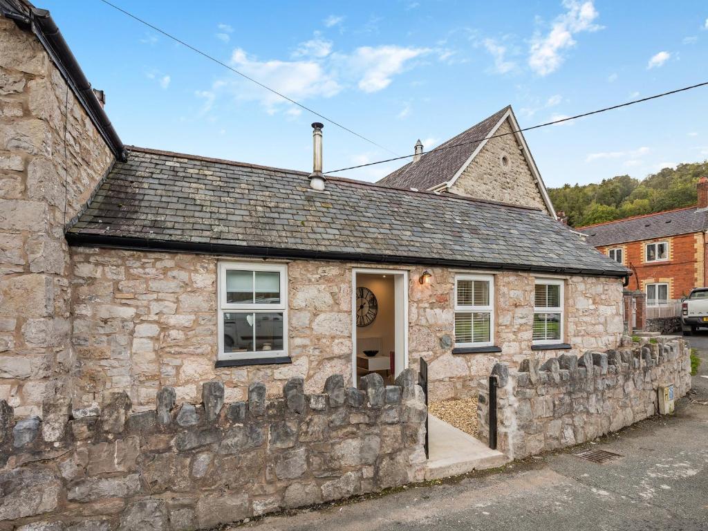 an old stone house with a stone wall at Rose Cottage in Llanfair-Dyffryn-Clwyd