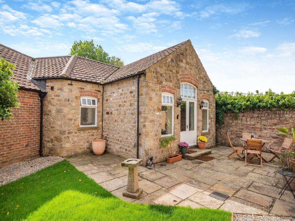 a brick house with a patio in the yard at Himba Cottage - Uk44767 in Ripon