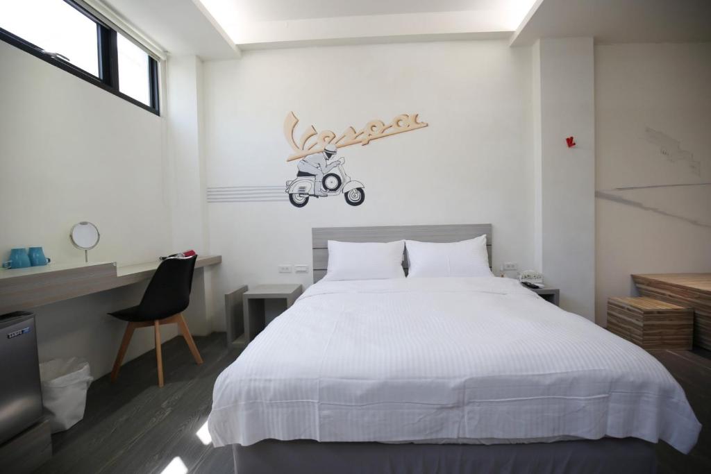 台南的住宿－樂宿保安 No.1 ，卧室配有白色的床,墙上挂着摩托车