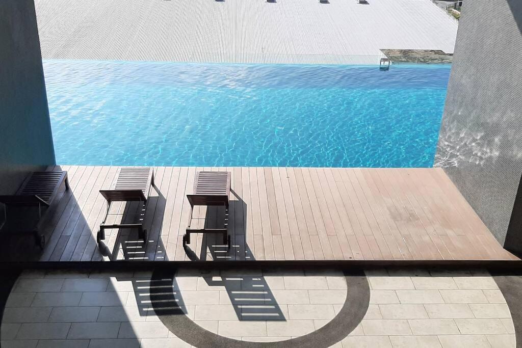 vista su una piscina con sedie e acqua di mozhouze studio @ 8 Kinrara Service Apartment a Puchong