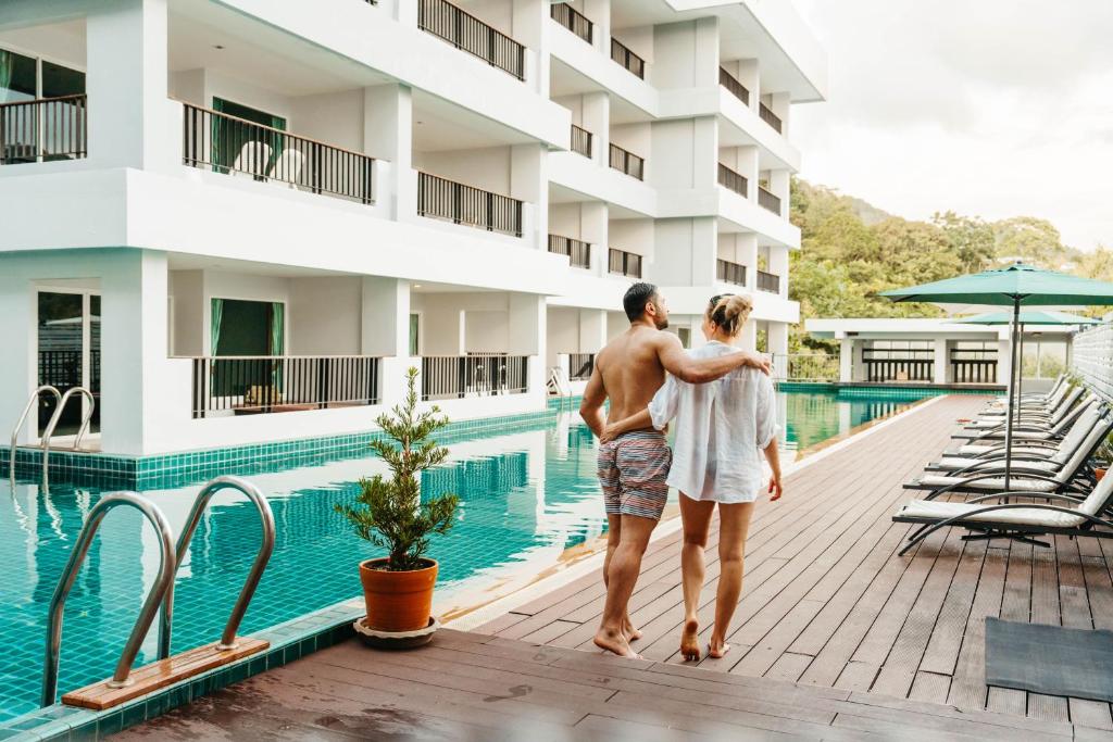 un hombre y una mujer parados junto a una piscina en Casa Del M Phuket, en Patong Beach