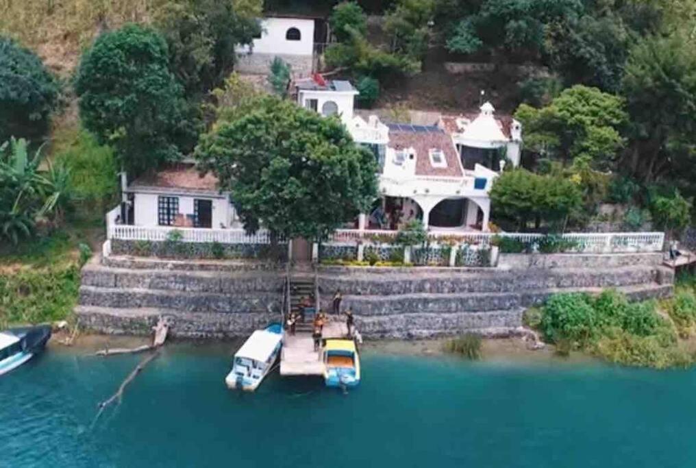 a house on a hill with boats in the water at El Castillo en el Lago Atitlán in San Marcos La Laguna