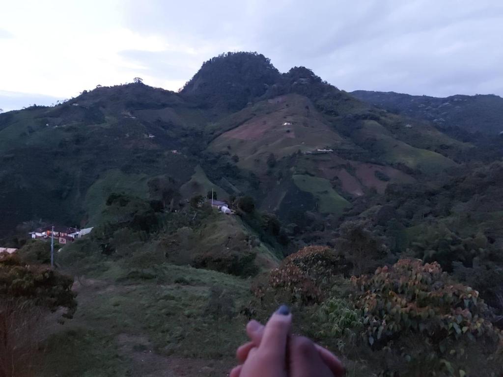 a person holding a remote control in front of a mountain at Preciosa cabaña en plena naturaleza con jaccuzi in Dosquebradas