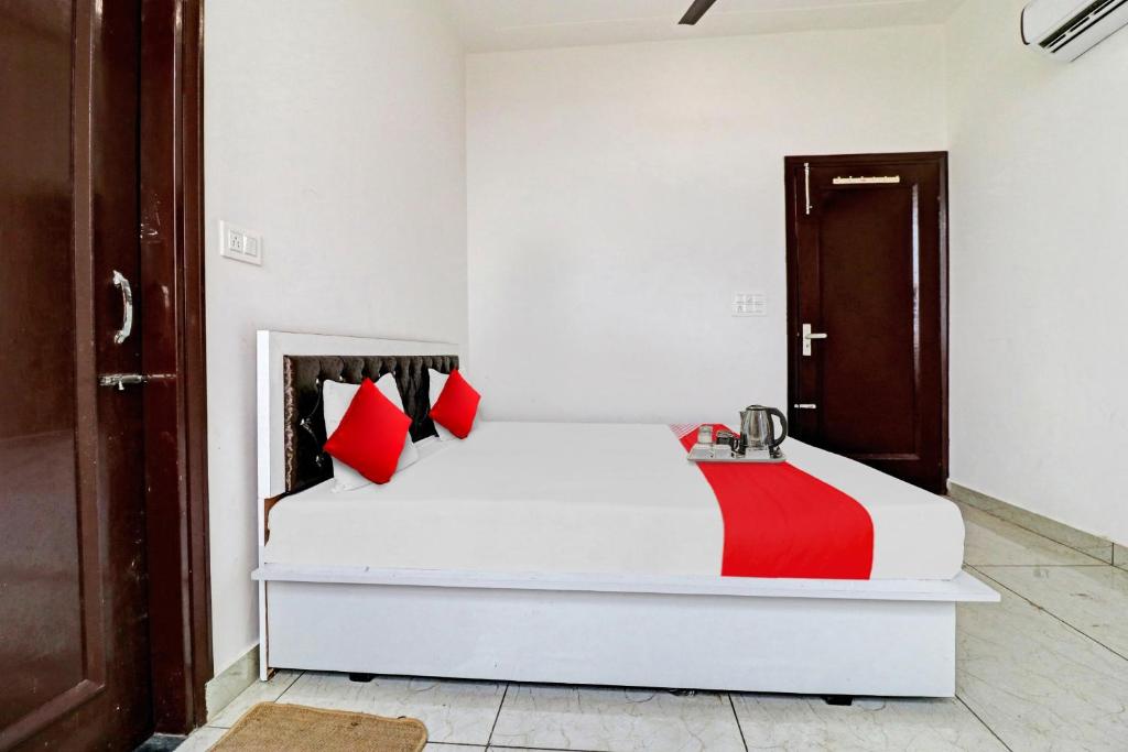 um quarto com uma cama branca e almofadas vermelhas em OYO Flagship Hotel Royal Inn em Patiala