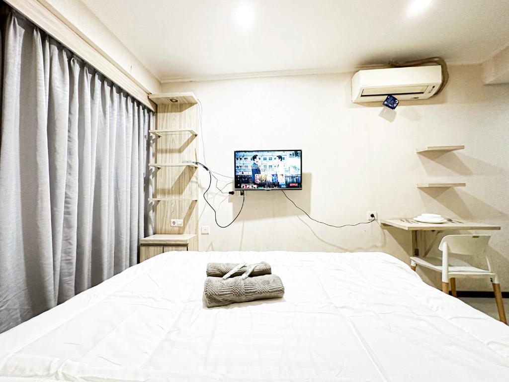 een ziekenhuiskamer met een bed en een tv bij Gateway Pasteur Apartment by RumahKu in Bandung