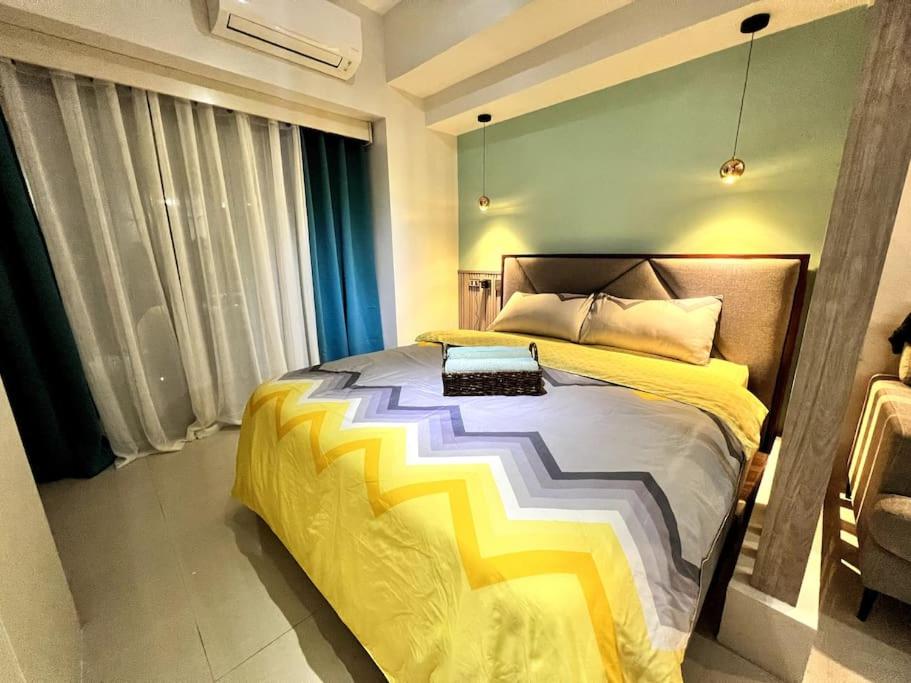 a bedroom with a bed with a yellow and white comforter at 1BR Condo beside Abreeza Mall, Davao City with 200 mbps WI-FI speed in Davao City
