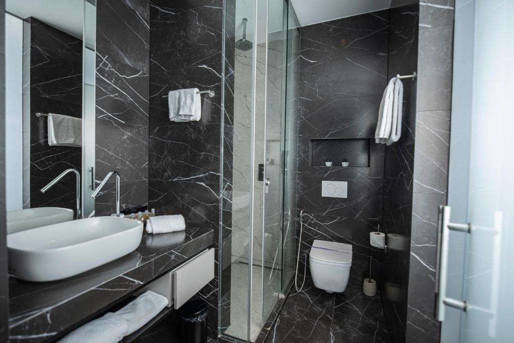 Venus Hotel في بريشتيني: حمام أسود مع حوض ومرحاض