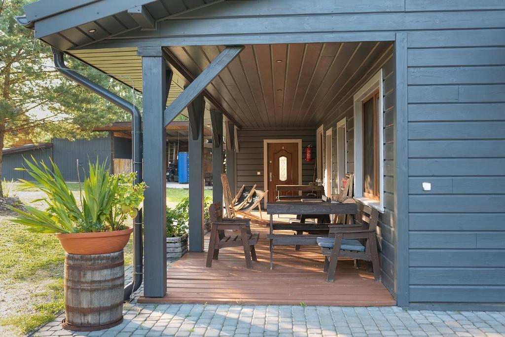 Casa azul con porche de madera y mesa de madera. en Farmstay Marianówka u Tesi en Giby