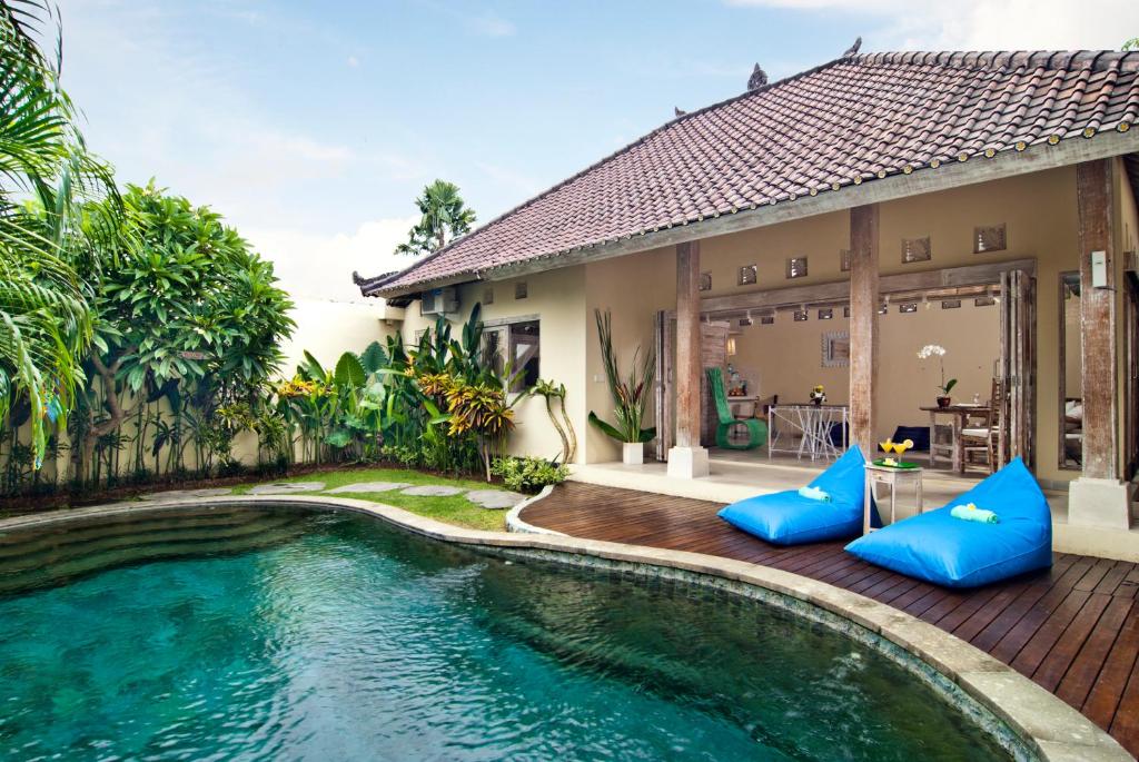 a villa with a swimming pool in front of a house at Villa Domus Dua in Seminyak