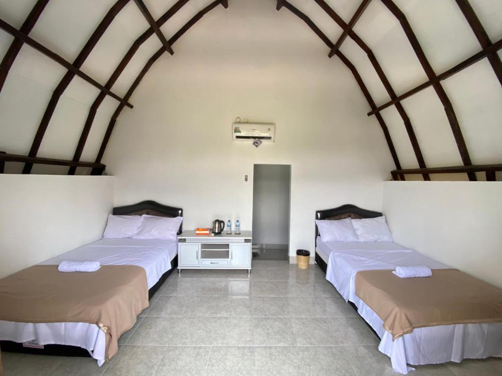 Zimmer mit 2 Betten und einem Schreibtisch. in der Unterkunft D'Liwatan Bungalow in Masbagik