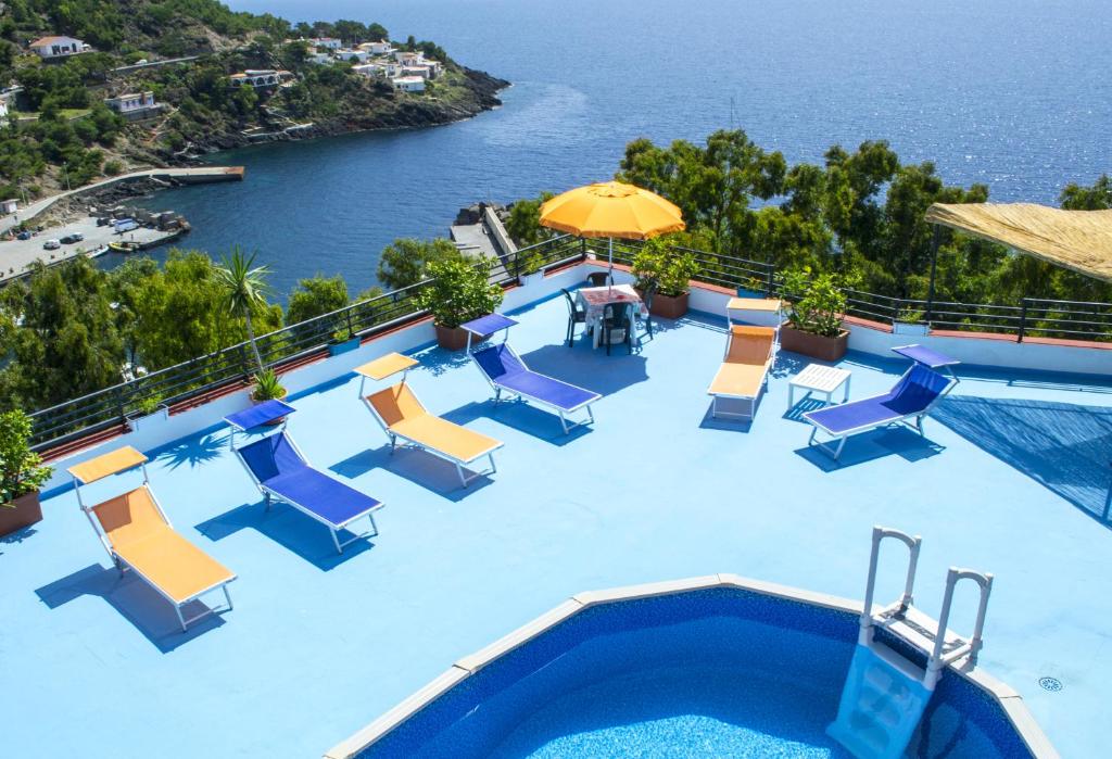 an infinity pool with chairs and an umbrella at Le Terrazze sul mare in Ustica