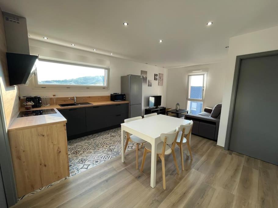 cocina y sala de estar con mesa blanca y sillas en Appartement climatisé en Charmes
