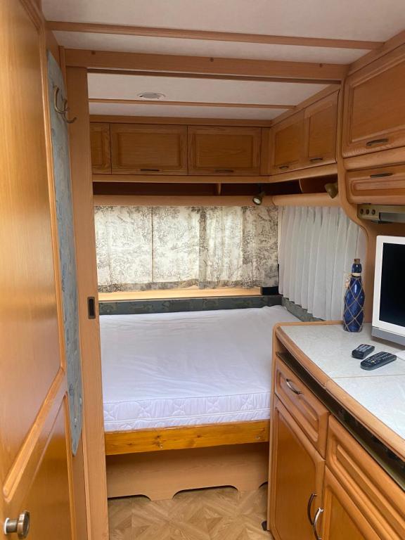un pequeño dormitorio en una caravana con una cama en ella en Wohnwagen auf dem Wulfenerhals, en Fehmarn