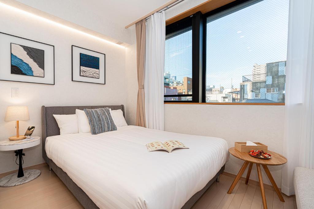 1 dormitorio con cama blanca y ventana grande en ZAITO Tokyo Narihira Hotel　押上駅から徒歩八分ホテル, en Tokio