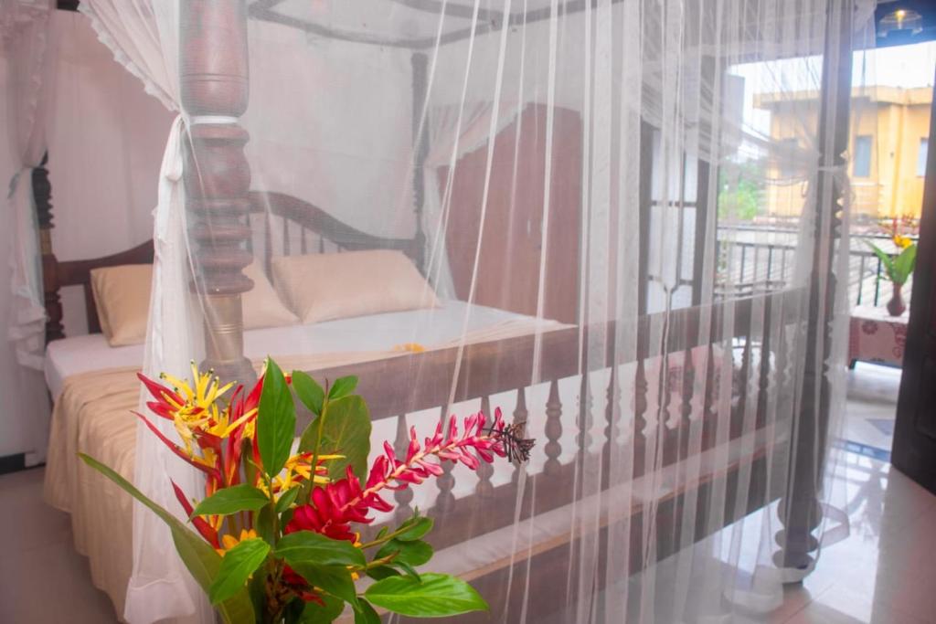 een slaapkamer met een bed en een raam met bloemen bij Winsi Villa in Unawatuna