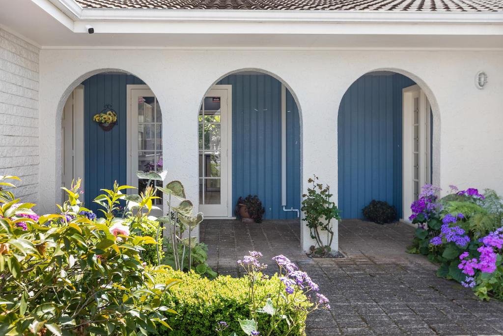 een huis met blauwe en witte deuren en bloemen bij Business Or Holiday with Location, Pool, 4 Bedroom in Hamilton