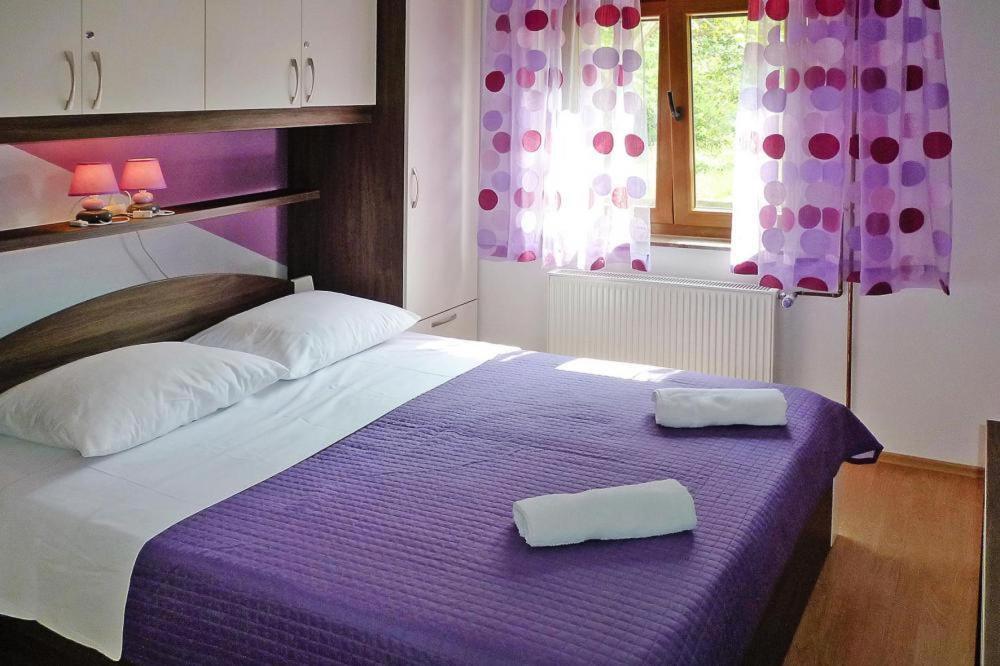 sypialnia z fioletowym łóżkiem z 2 ręcznikami w obiekcie Apartment PINK in Starigrad Paklenica only 200 m from the sea w mieście Starigrad-Paklenica