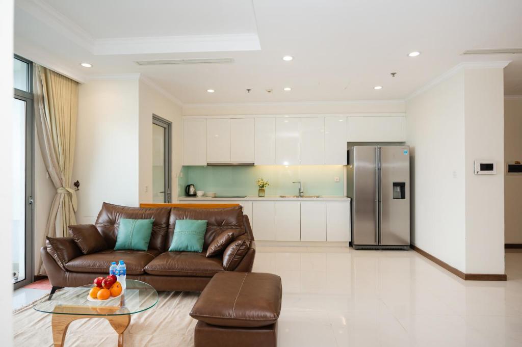 un soggiorno con divano marrone e una cucina di Vinhomes Landmark Apartment - CirillaHome ad Ho Chi Minh