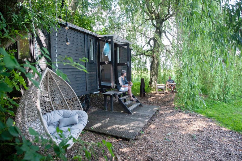 a man sitting on a porch of a blue tiny house at Tiny House met sauna, vrij uitzicht, midden in de natuur 