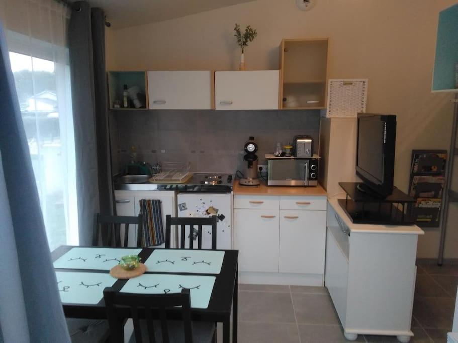uma cozinha com uma mesa com cadeiras e uma televisão em Le studio médocain em Cussac-Fort-Medoc