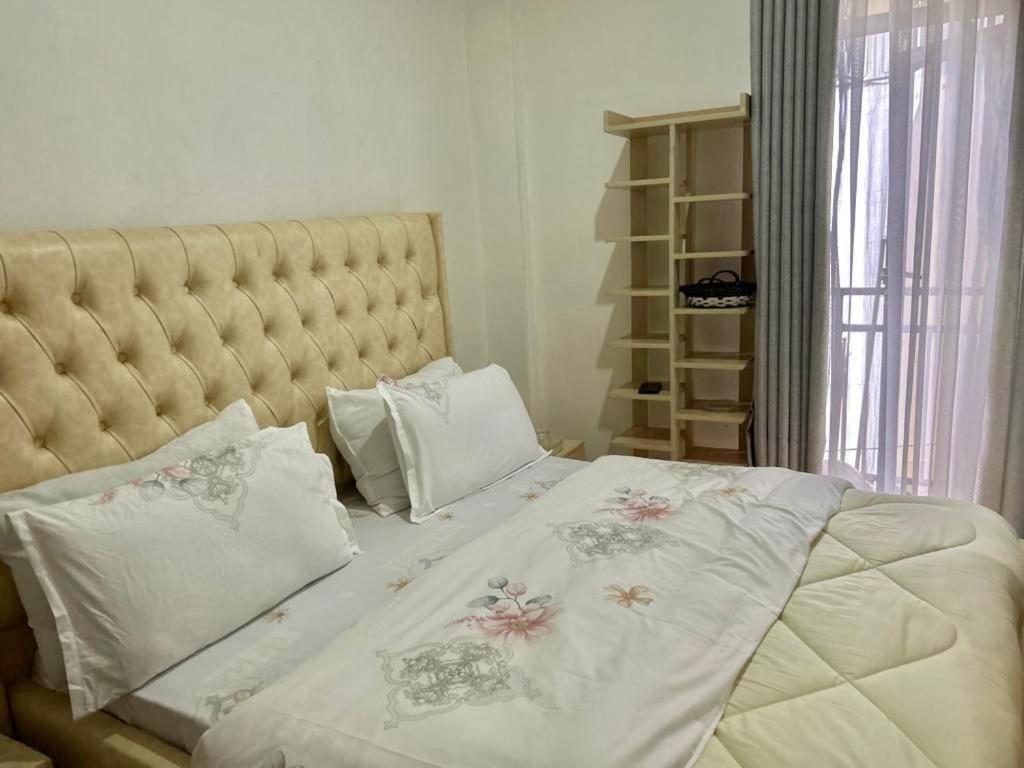 um quarto com uma cama grande com lençóis brancos e almofadas em Kigali Swift Rentals em Kigali