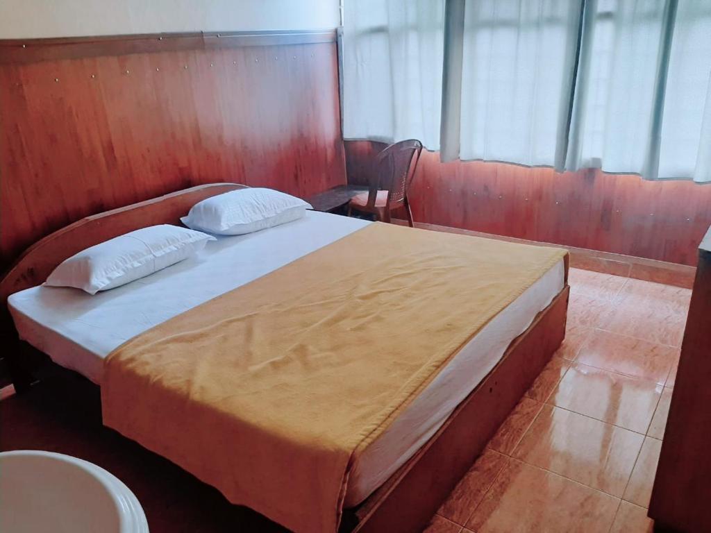 1 dormitorio con 1 cama grande y 2 almohadas en Vega Residency And Bike Rentals en Madikeri
