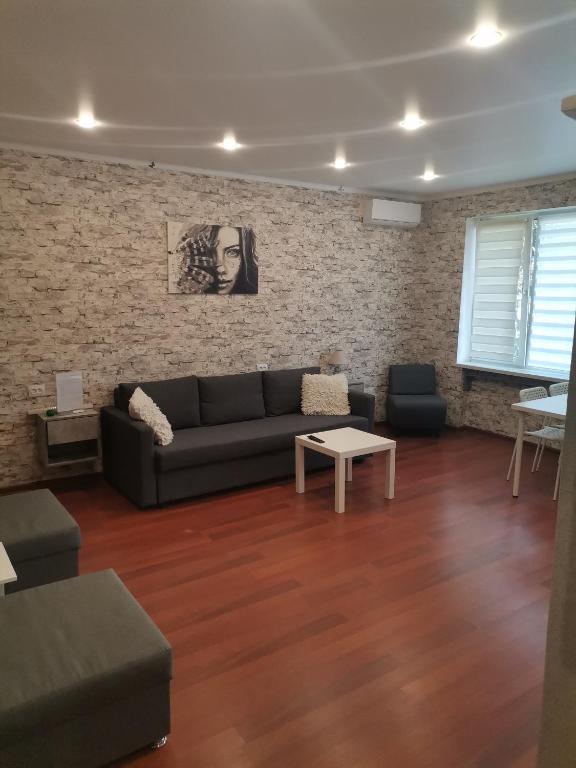 a living room with a couch and a brick wall at Однокомнатная квартира-студия в Гагре! Море солнца in Gagra