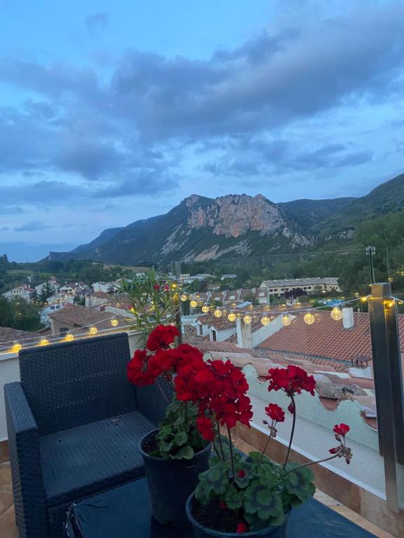 a balcony with red flowers and a view of a mountain at El mirador de Mati in Torrecilla en Cameros