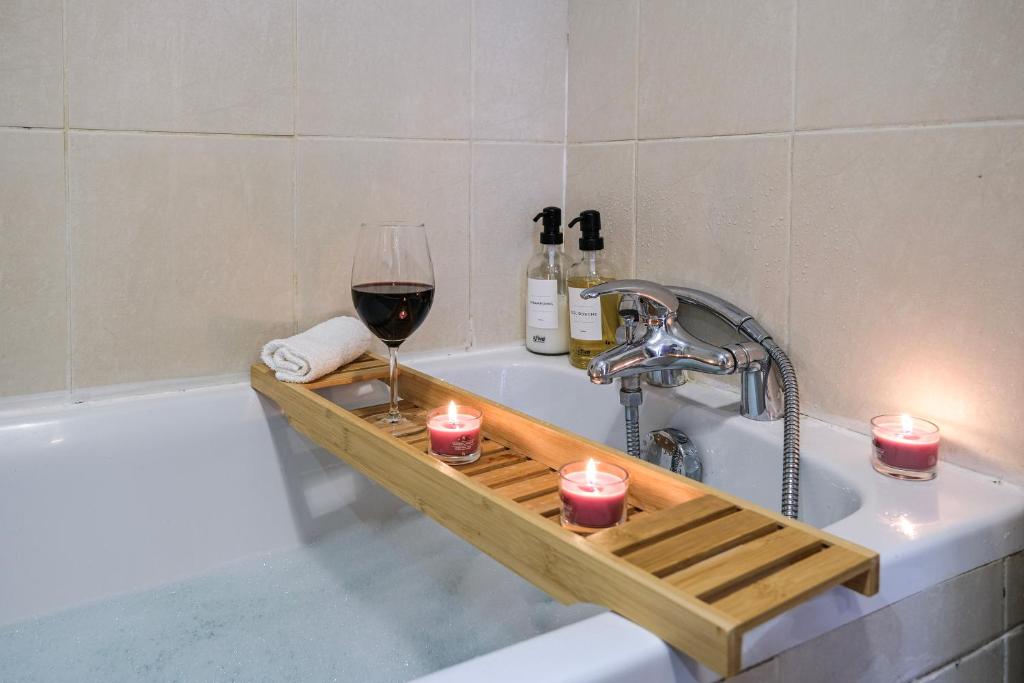 a bath tub with a glass of wine and candles at Numéro 6 - Place Nationale - Wifi et Fibre in Montauban