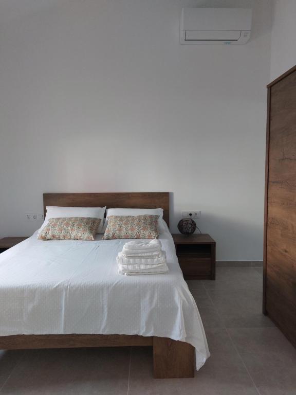 a bedroom with a white bed with a wooden headboard at La Casica in Benijófar