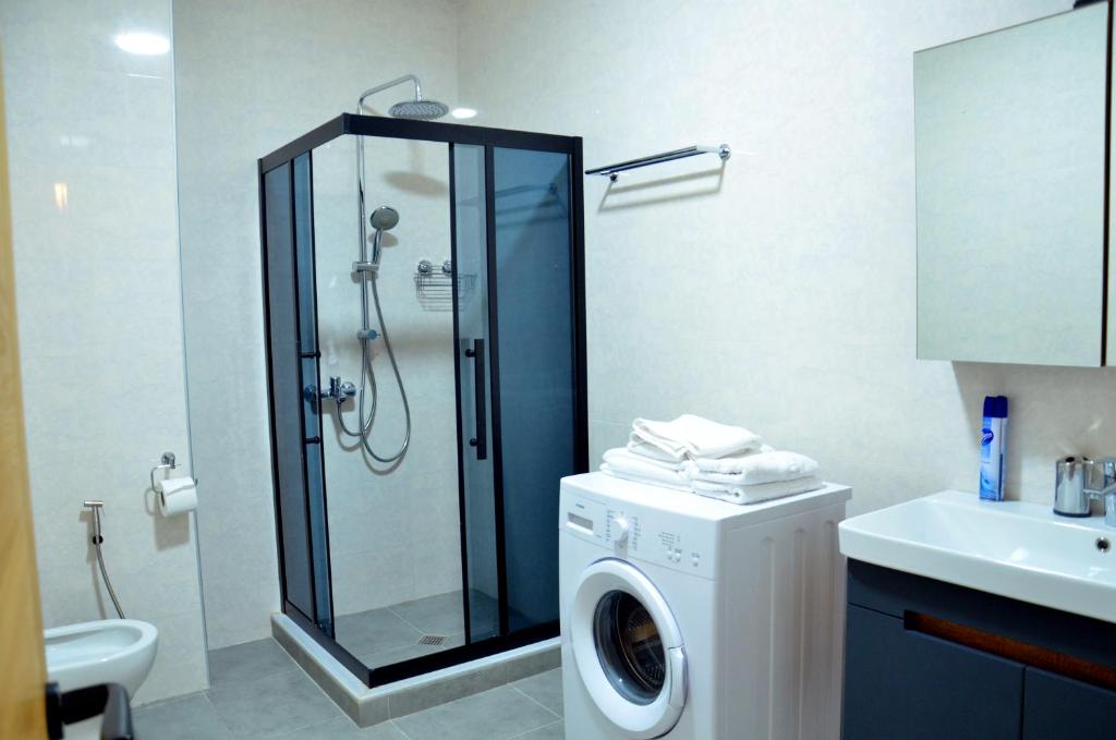 a bathroom with a shower and a washing machine at Season Suite Apart-Hotel in Batumi
