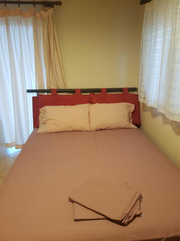 a bed with a red head board and white pillows at The Quiet Corner in Kalamata