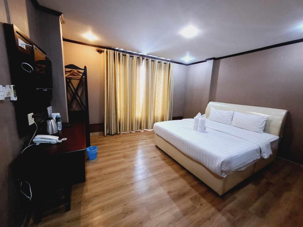 Schlafzimmer mit einem weißen Bett und Holzboden in der Unterkunft Sinakhone Vientiane Hotel in Vientiane