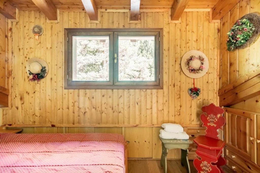 una camera con letto, finestra e tavolo di Chalet Pian della Velma a Giralba